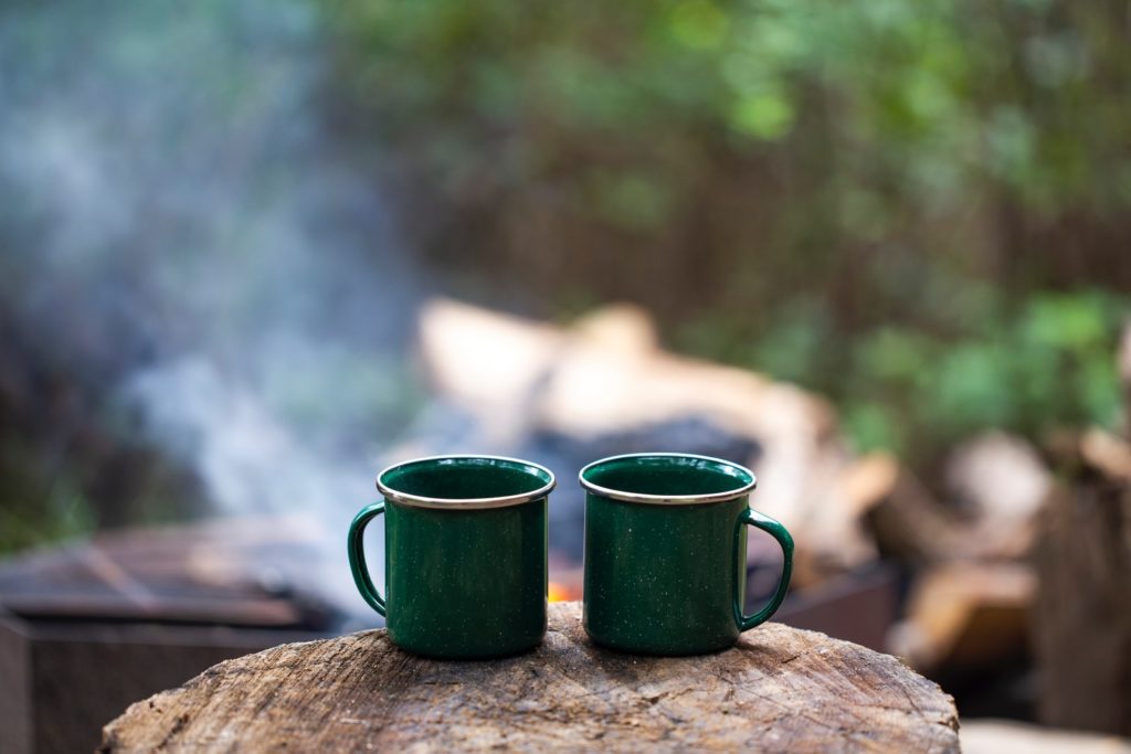 2 green ceramic mugs on brown wooden log